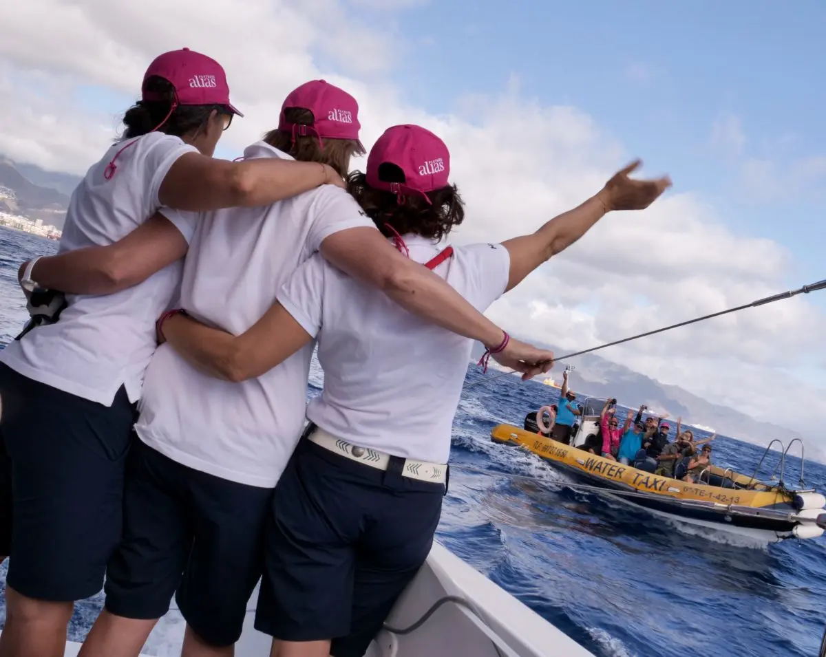 Photo équipage faisant des signes à un groupe de personnes sur un bateau pneumatique